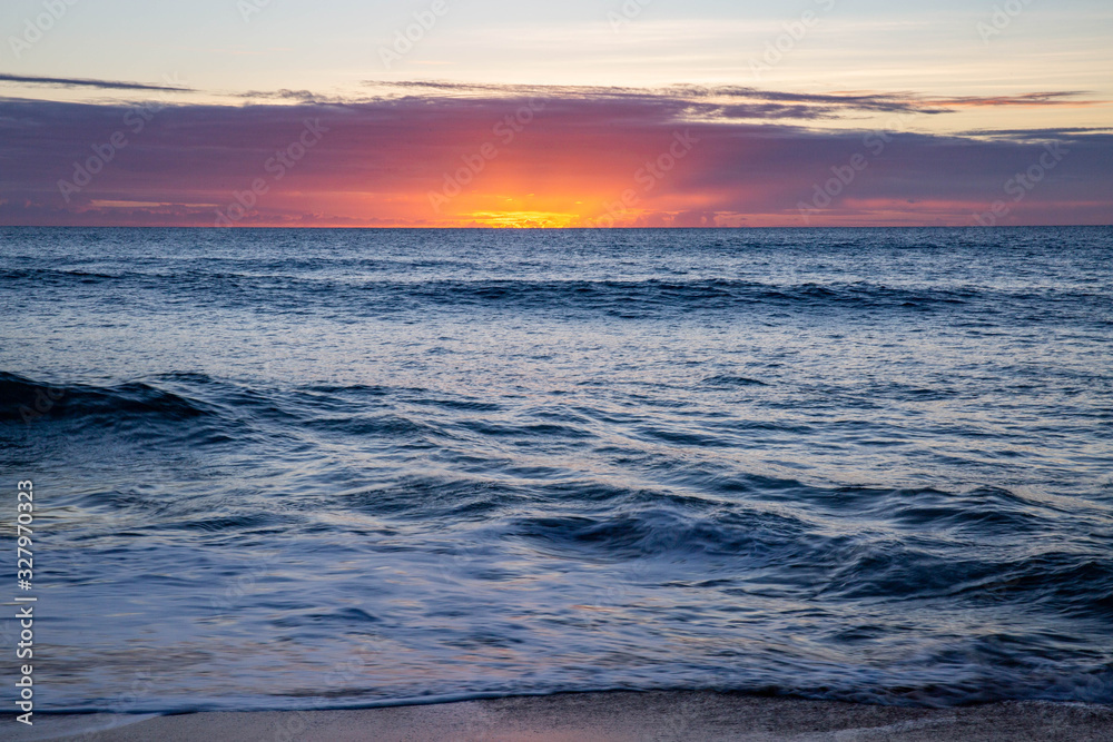Obraz premium calming ocean waves over pink hawaiian sunset