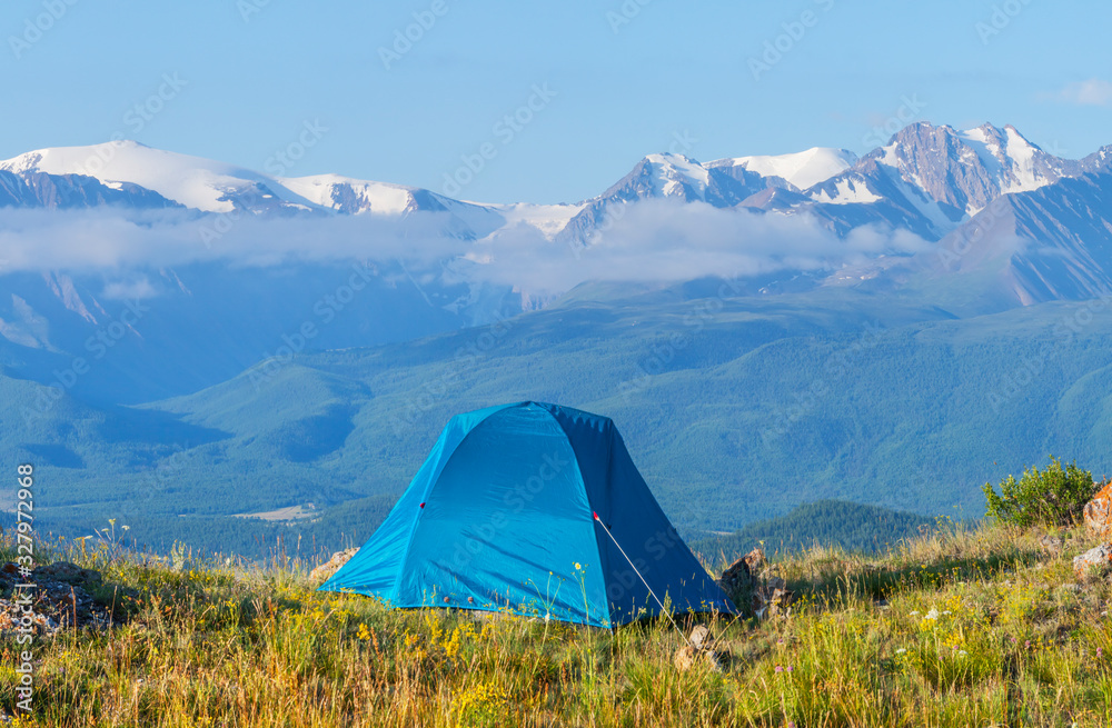 Tent on a background of snow-capped peaks, mountain tourism