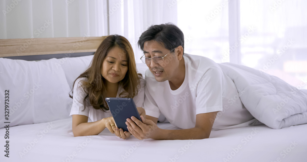 Happy asian couple watching tablet together in a bedroom. Happy asian couple watching tablet together in a bedroom.