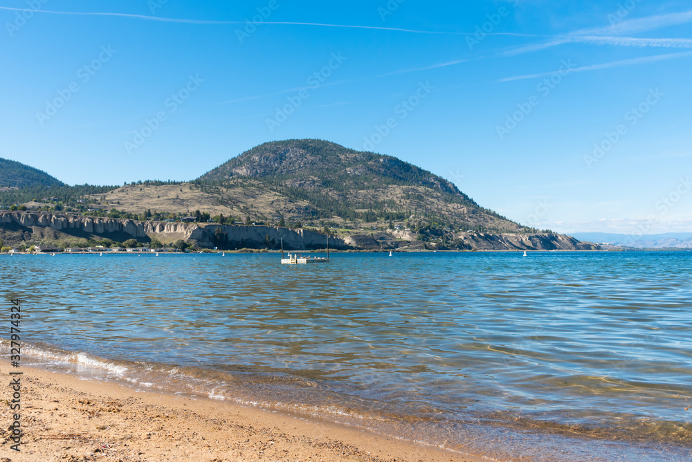 View of sandy beach, Okanagan Lake, Blue Mountain and sky in summer in Penticton