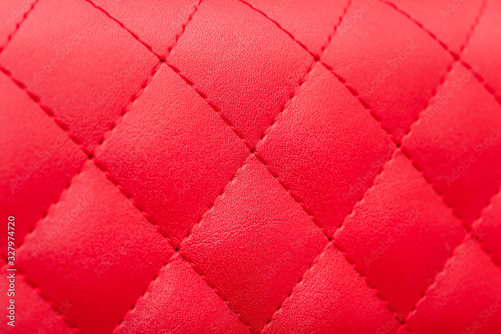Fototapeta premium red leather pattern stitched squares with thread seam, decorative texture of animal skin, side view.