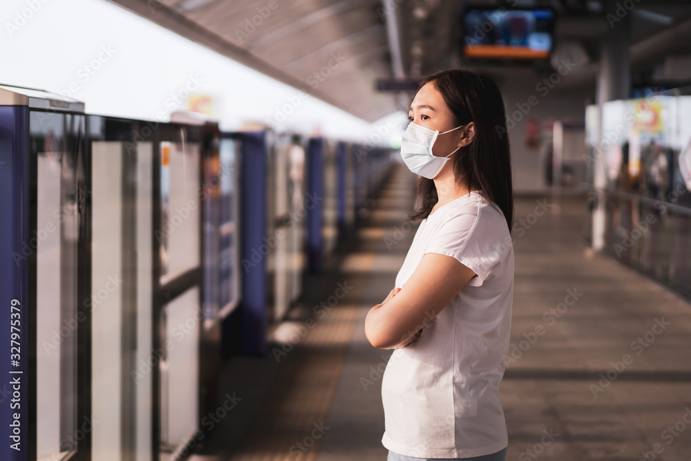 Beautiful young Asian woman wearing the protective mask while traveling in the city where fully with air pollution pm2.5. Unhealthy urban air pollution problem and coronavirus disease in Asia.