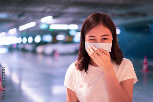 Worried Asian woman wearing a protective mask during poor air quality in the city. Air pollution problem in urban area may cause of illness and sickness in people. Woman worried about coronavirus.