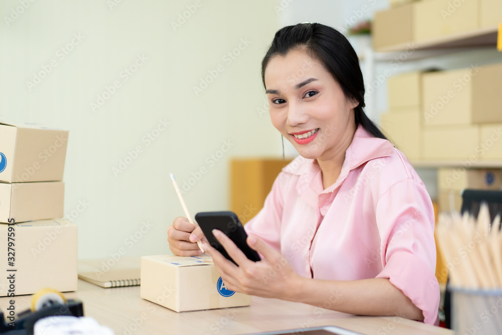 Young Asian business woman packing a post boxes to be shipped to customers. Ecommerce online shopping concept. Expertise online sales person packing customers parcel boxes for shipment. Young Asian business woman packing a post boxes to be shipped to customers. Ecommerce online shopping concept. Expertise online sales person packing customers parcel boxes for shipment.