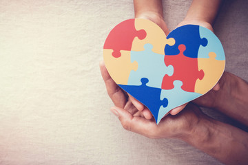 Adult and child hands holding puzzle jigsaw heart,  mental health concept, world autism awareness day, , Autism spectrum disorder concept