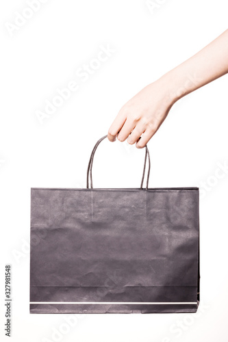 Woman hand hold a black shopping bag isolated on white.