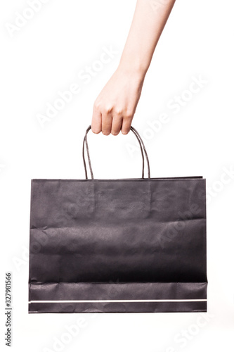 Woman hand hold a black shopping bag isolated on white.
