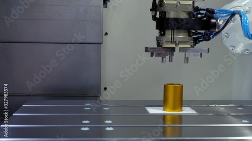  Close-up Industrial robotic using grip arm catch golden metal workpiece and put silver metal workpiece to replace on CNC machine on smart factory, Industry 4.0 technology, copy space
