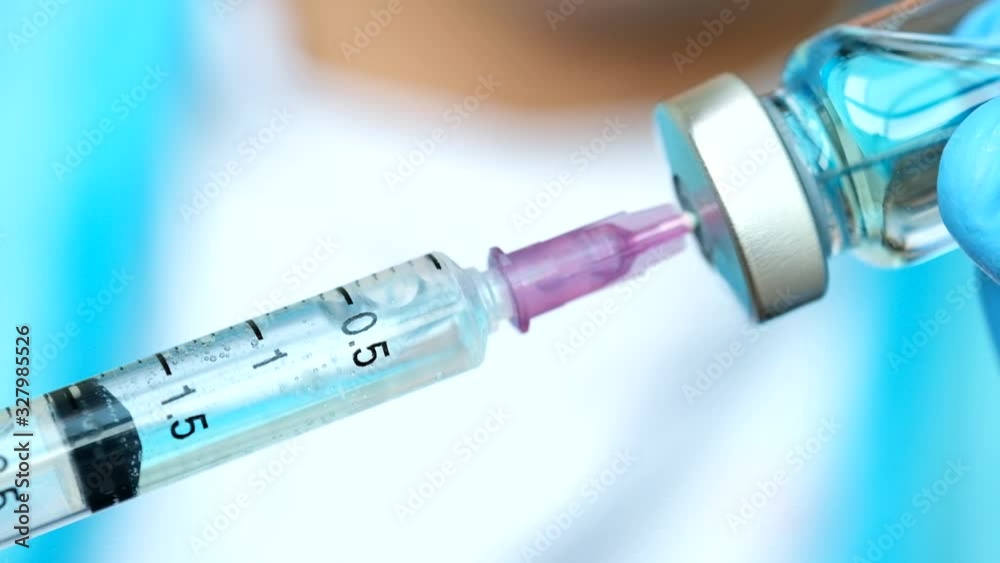 doctor's hand holds a syringe and a blue vaccine bottle at the hospital. Health and medical concepts doctor's hand holds a syringe and a blue vaccine bottle at the hospital. Health and medical concepts