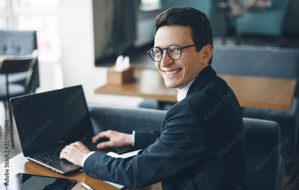 Caucasian man typing something at the computer and looking cheerfully back to camera