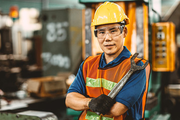 Portrait of Asian Thai Chinese labor happy worker enjoy happy smiling to work in a heavy industrial factory to fix machine with big wrench.