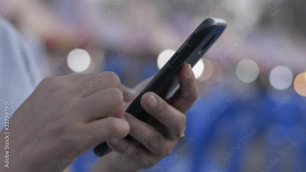 Close up woman hands using mobile smart phone for social online at street food market. Wireless technology concept. Lighting bokeh background. Close up woman hands using mobile smart phone for social online at street food market. Wireless technology concept. Lighting bokeh background.