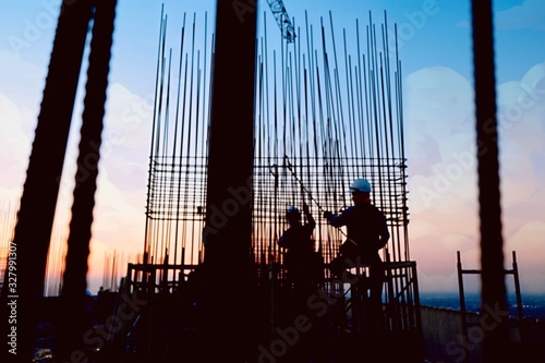 Burred of construction of rooftop high rise building, workers are tied with steel bars for concrete pouring, survey the site and crane are lifting or moving metal at the construction site. Pastel tone