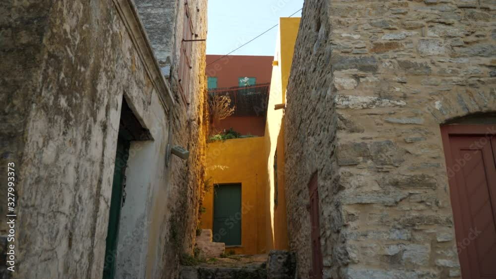 Low angle view on a narrow street with yellow house in Symi Island, Greece Low angle view on a narrow street with yellow house in Symi Island, Greece