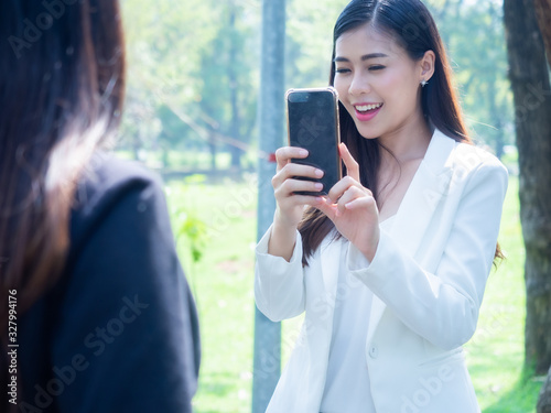 happy asia business woman wearing suit take photo selfie together in park copy space