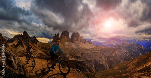 Cycling outdoor adventure in Dolomites. Cycling woman and man on electric mountain bikes in Dolomites landscape. Couple cycling MTB enduro trail track. Outdoor sport activity.
