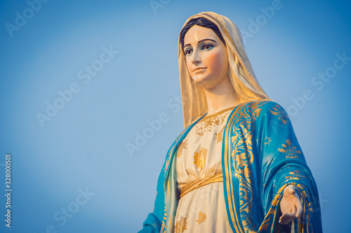 Close-up of the blessed Virgin Mary statue figure. Catholic praying for our lady - The Virgin Mary. Blue sky copy space on background.