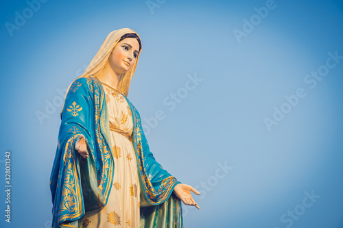 Close-up of the blessed Virgin Mary statue figure. Catholic praying for our lady - The Virgin Mary. Blue sky copy space on background. photo