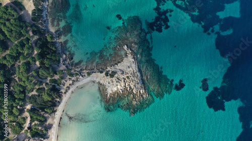 Aerial view of Vourvourou beach, small peninsula in turquoise water of Aegean sea. Waves beating cliff rocky coastline. Halkidiki, Greece. © dimabucci