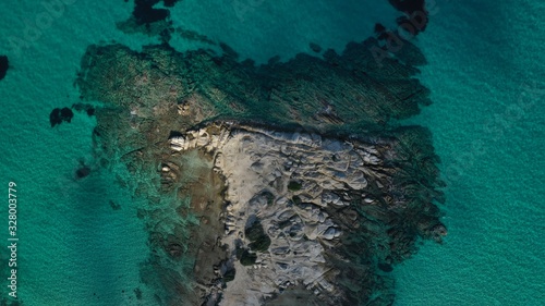 Aerial view of Vourvourou beach, small peninsula in turquoise water of Aegean sea. Waves beating cliff rocky coastline. Halkidiki, Greece.