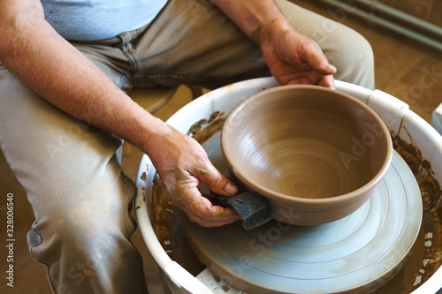 Professional potter working at kick wheel in home studio. Handmade mastery concept. Artisan at workshop.