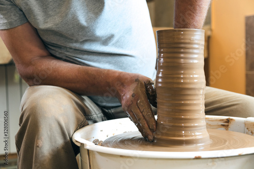Portrait of craftsman working with clay in pottery workshop. Small business concept.