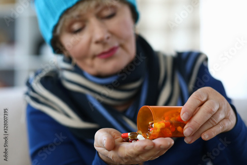 Elderly woman puts capsules from can in palm. Undesirable effects drugs. Use drug in therapeutic doses. Danger to elderly person. Serious chronic diseases frequent companion aging