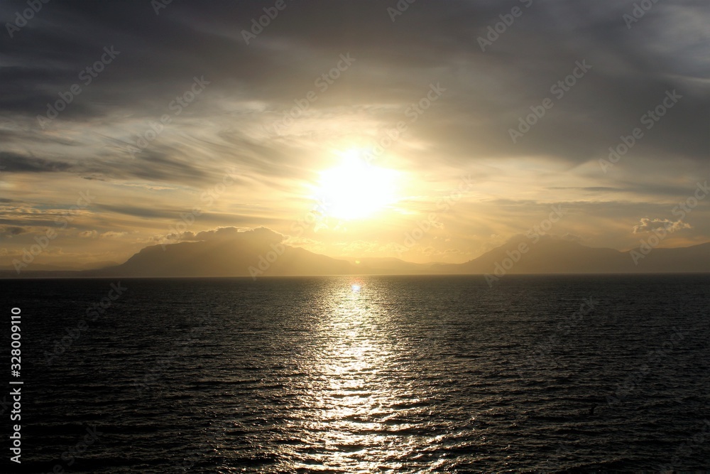 evocative image of sunset over the sea with headland silhouette in the background