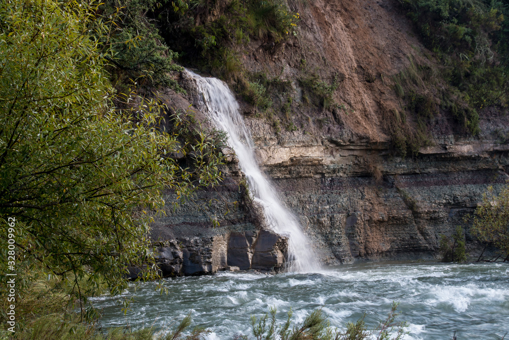 Obraz premium Small Cascading Waterfall Flowing into River