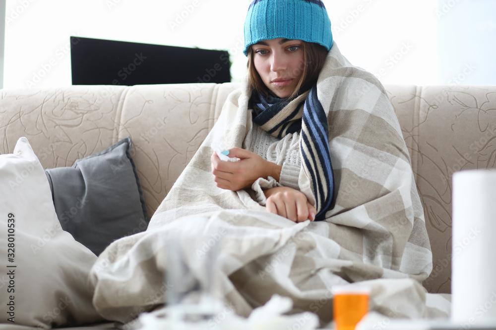 Portrait of ill woman looking away with sadness and calmness. Beautiful female taking medication. Person trying to keep warm. Sickness and treatment concept Portrait of ill woman looking away with sadness and calmness. Beautiful female taking medication. Person trying to keep warm. Sickness and treatment concept