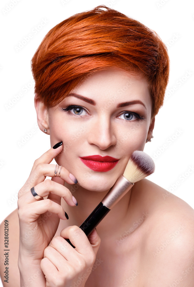 Portrait of a beautiful young woman with short red hair with a makeup brush Portrait of a beautiful young woman with short red hair with a makeup brush