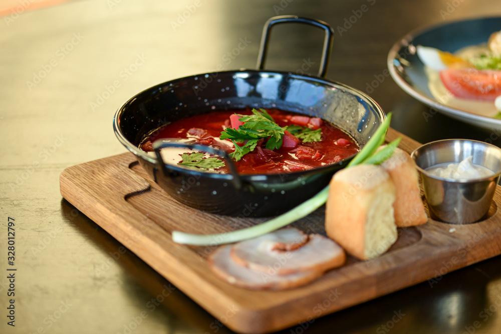 Traditional Ukrainian Russian vegetable borscht served in a black bowl on the old wooden background. Traditional Ukrainian Russian vegetable borscht served in a black bowl on the old wooden background.