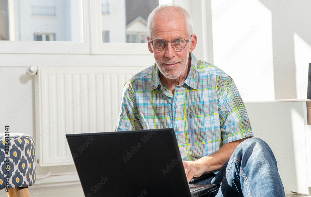 senior man sitting on floor and using laptop senior man sitting on floor and using laptop