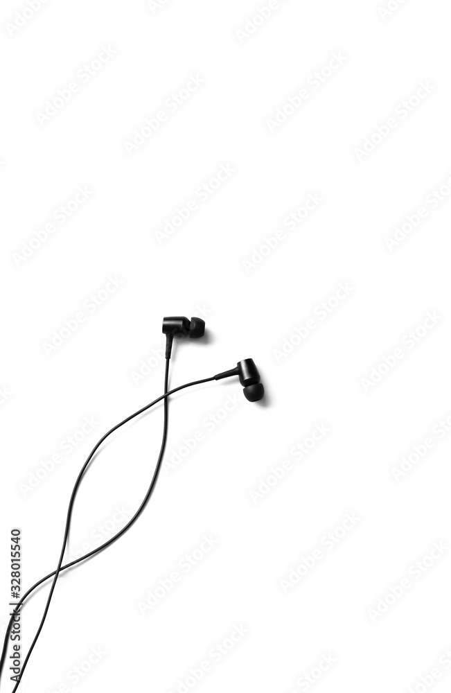 Obraz premium Black earphones lying on the white background. Modern music concept. Audio technology.