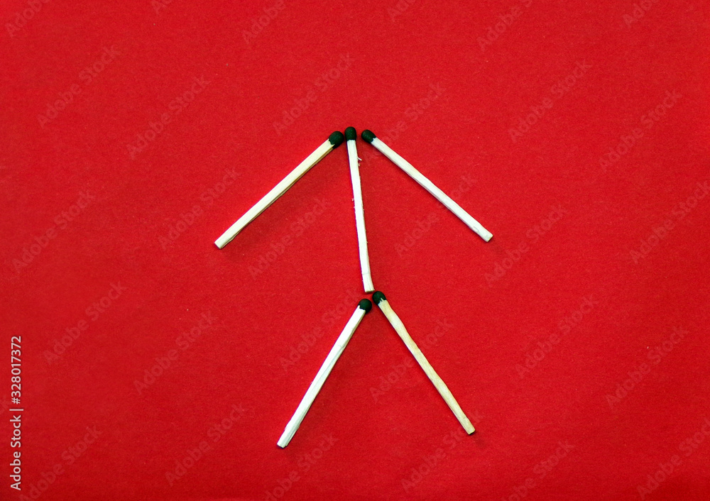 The figure and icon of a man is laid out of matches on a red background. The symbol of man of the matches. Creative and original symbol. The figure and icon of a man is laid out of matches on a red background. The symbol of man of the matches. Creative and original symbol.
