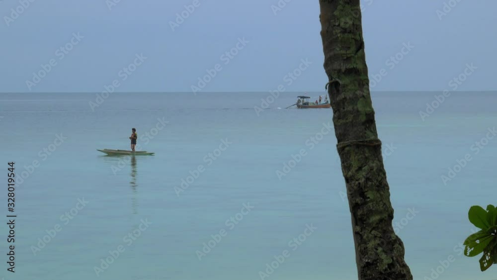 Exotic scenery composed of a palm tree, fisherman and long-tail boat in the background. Exotic scenery composed of a palm tree, fisherman and long-tail boat in the background.