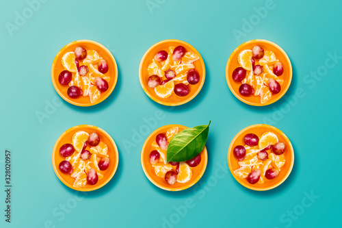 Fruit Pieces of Grape and Mandarin - Salad in Orange Bottles with One Green Lemon Leaf on Blue Background. Healthy Breakfast Lifestyle Concept.
