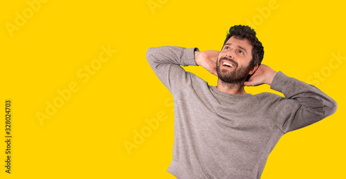 young handsome man smiling with a happy, confident expression, wondering and looking to the side over yellow background