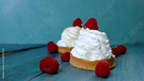Beautiful cupcake with white whipped cream and raspberries on a blue wooden background, breakfast concept