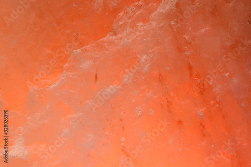 Piece of salt with orange backlight for the background. Crystal structure.