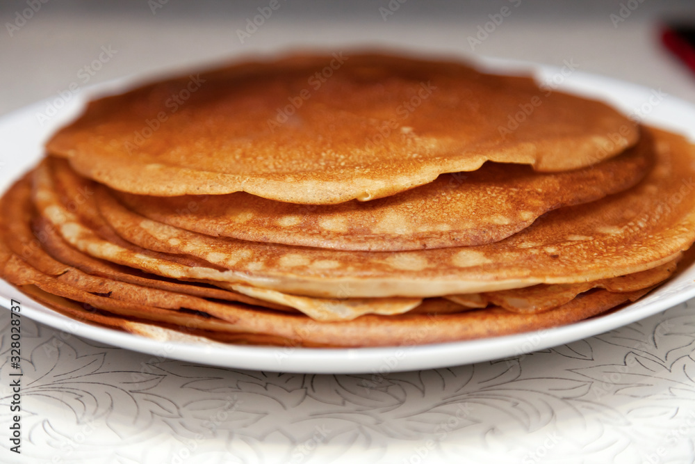 A stack of delicious hot and fresh thin pancakes baked in a pan of milk, flour and eggs for breakfast at home. Russian national holiday Shrovetide. A stack of delicious hot and fresh thin pancakes baked in a pan of milk, flour and eggs for breakfast at home. Russian national holiday Shrovetide.