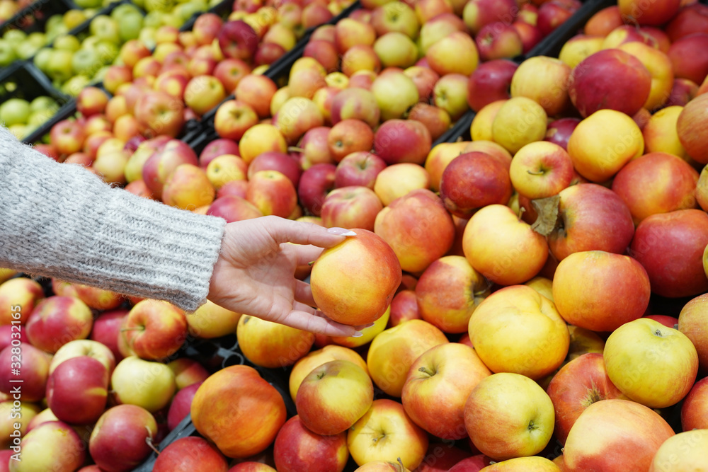 Female hand choosing red fresh apples at market stall Female hand choosing red fresh apples at market stall