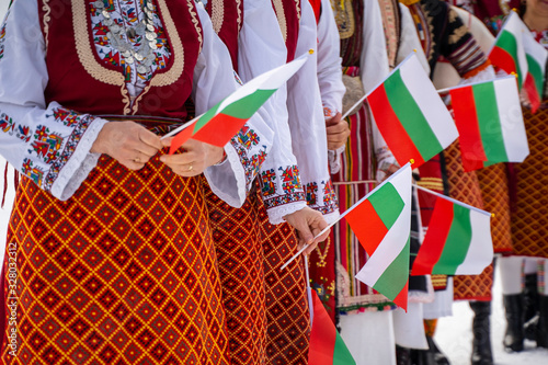 Bulgarian Flag. Woman holding Flag of Bulgaria in traditional clothing. Day of Liberation parade. National holiday with people celebrating. Patriotic scene people waving flags. photo