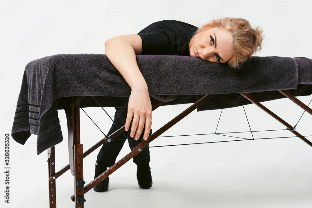 Φωτογραφία Portrait of young cheerful friendly woman masseur in uniforme near massage table in wellness center