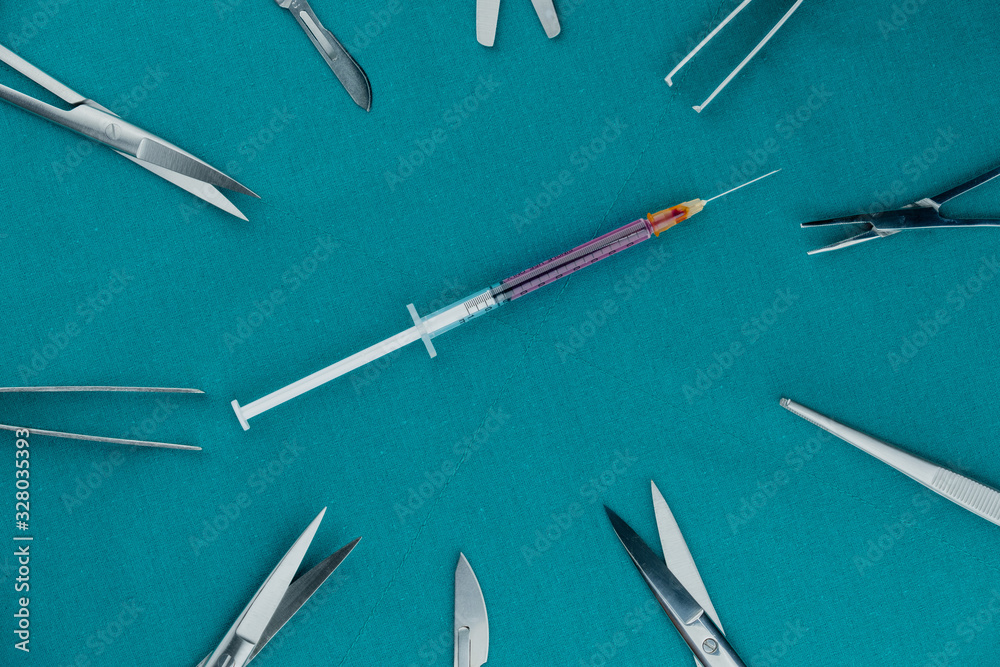 Top view of surgical instrument, liquid parenteral products in syringe with scalpel, tweezers, scissors on surgical green drape fabric. Top view of surgical instrument, liquid parenteral products in syringe with scalpel, tweezers, scissors on surgical green drape fabric.