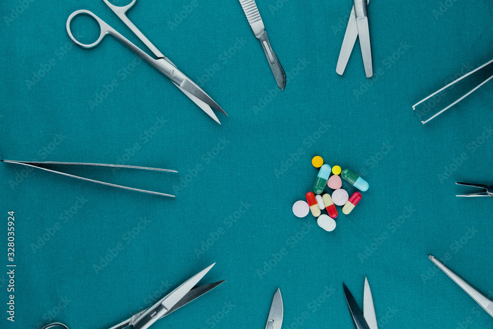 Φωτογραφία Top view of pills drugs tablets and capsules with basic surgical instrument, scalpel, tweezers, scissors on surgical green drape fabric