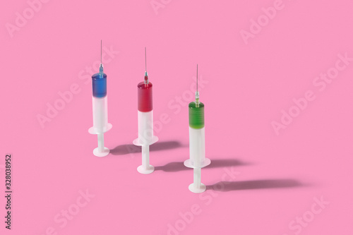 Vertical plastic syrenges with colorful liquid stanging on background. photo