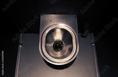 Stylish steel toilet in a dark public toilet photo