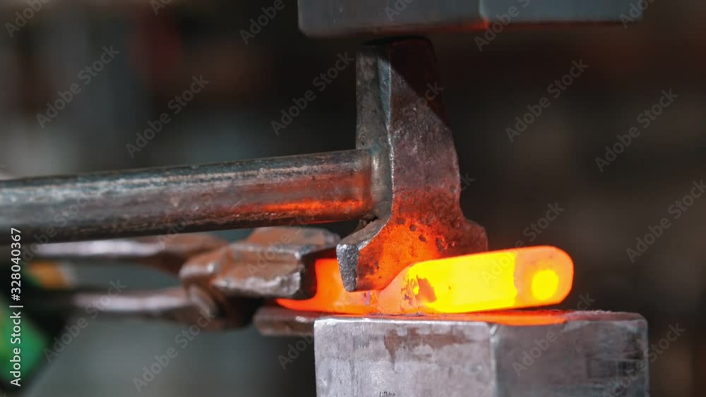 Blacksmith cutting the piece of incandescent metal with an axe and industrial forging pressure machine Blacksmith cutting the piece of incandescent metal with an axe and industrial forging pressure machine
