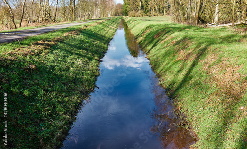 Foto Drainage ditch to drain the moor area, with embankments with grass